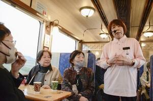 のと鉄道の「震災語り部観光列車」で乗客に被災体験を伝える宮下左文さん(右)=4月6日午前、石川県七尾市