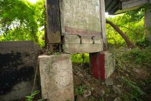 不安定な土台に乗る、崩れ残った赤い家の壁＝２０２５年１２月、フィリピン・サンイルデフォンソ