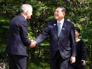 G7サミット会場のカナダ西部カナナスキスで、カナダのカーニー首相(左)の出迎えを受ける石破首相=16日(共同)
