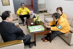 新1年生のお守りを贈り、浅野哲司校長(左)に説明する髙昭子部会長(手前右)=田上町羽生田