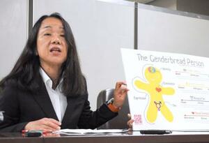 社内研修で使われたという資料を手に、記者会見する原告の土多恵子さん=25日午後、東京・霞が関の司法記者クラブ