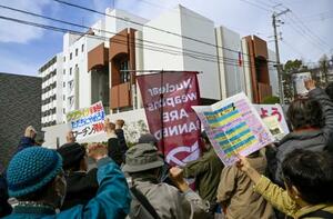 　在大阪ロシア総領事館（奥）の前で、ウクライナ侵攻に抗議する人たち＝２４日午後、大阪府豊中市