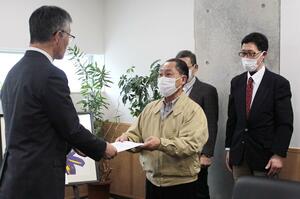 柏崎市の桜井雅浩市長(左)に柏崎刈羽原発の再稼働を認めないよう求めた申し入れ書を手渡す「原発を再稼働させない柏崎の会」のメンバー=2月20日、柏崎市役所