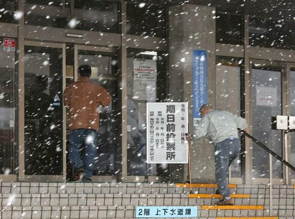 吹雪の中、期日前投票所に入っていく人たち＝３１日、三条市下田庁舎
