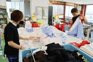 クリーニング店を経営する男性(右)。最低賃金を巡る議論に注目している=新潟市東区