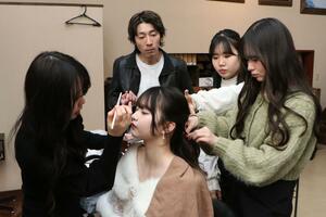 美容師(奥の男性)の指導を受けながらモデルのスタイリングをする高校生ら=南魚沼市美佐島