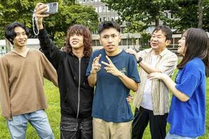 　久しぶりに再会した平田和毅（中央）らをスマートフォンを掲げて撮影する谷口莉乙（左から２人目）。右から狩野はな、中学時代の担任の曽我部昌広、左端は本間大雅＝２０２５年８月、札幌市（撮影・藤井保政）