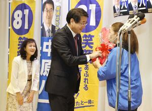 再選を決め、選対スタッフから花束を受け取り笑顔を見せる中原八一さん=10月23日午後8時半ごろ、新潟市中央区