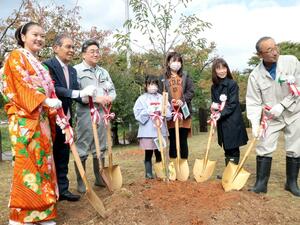 サクラの若木を植樹する関係者=佐渡市真野