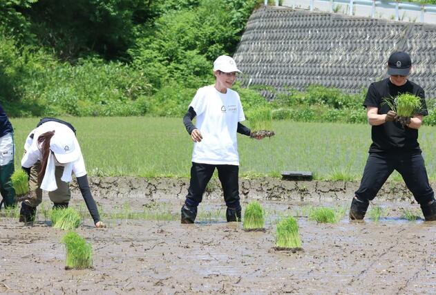 おにぎりぼんごのスタッフらと田植えをした右近由美子さん(中央)=関川村小和田