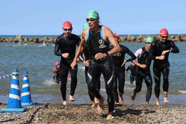 スイムの折り返しのため砂浜に上がる選手たち＝村上市瀬波温泉１