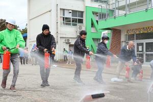 訓練用の消火器で初期消火を練習する住民ら=10月20日、十日町西小学校