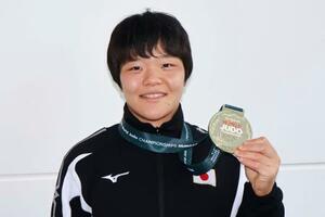 柔道の世界選手権から帰国し、女子63キロ級で獲得した金メダルを手にポーズをとる嘉重春樺=18日、羽田空港