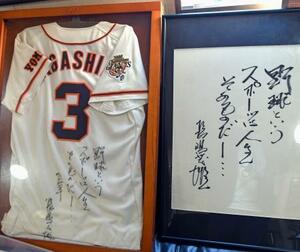 　石井彰英さんが所有する、長嶋さんのサイン入りユニホーム（左）と座右の銘を記した直筆の色紙＝５月、東京都内