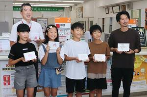 砂丘桃をPRするメッセージカードを生産者に手渡した刈羽小の6年生=刈羽村正明寺