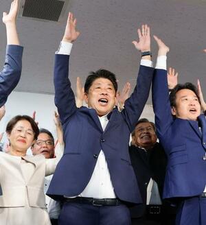 福岡選挙区で当選を決め、万歳する公明党の下野六太氏(中央)=21日未明、福岡市