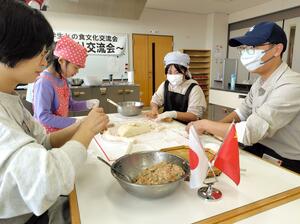 力を合わせて水ギョーザを作る参加者＝聖籠町諏訪山