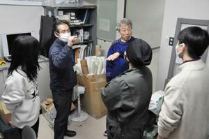 　定時制科学部の生徒や教員と実験方法について話し合う久好圭治さん（右奥）