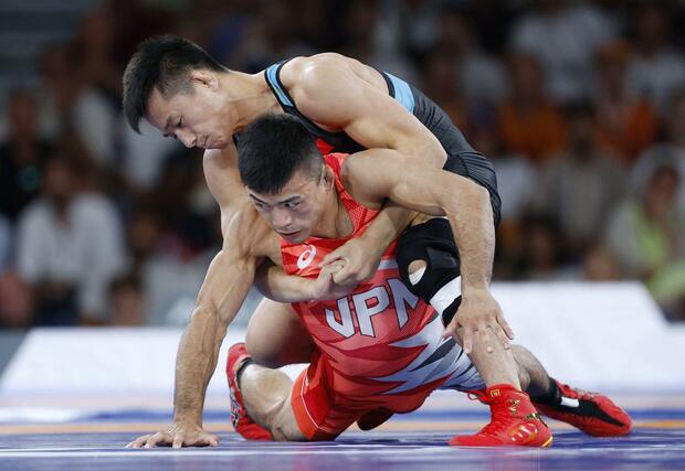 男子グレコローマン６０キロ級決勝　中国選手（上）の攻めをこらえる文田健一郎＝パリ（共同）
