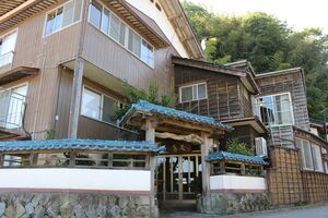 旧旅館「泉屋」を宿泊施設に再生した「GLOCEベースキャンプ松ケ崎」。玄関前にかつての看板が飾られている=佐渡市多田