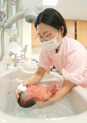 赤ちゃんの小さな頭や体を丁寧に洗う助産師。赤ちゃんは泣いたり、気持ちよさそうにしていたりと、さまざまだ=三条市