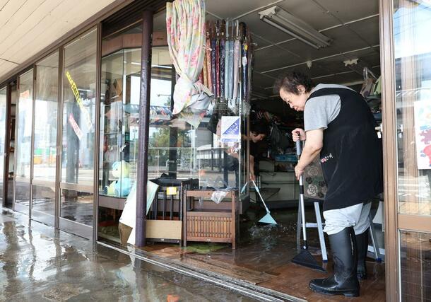 大雨で水に漬かった店舗を片付ける市民=3日、上越市中央1
