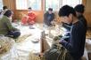鬼太鼓で使うわらじを編む参加者＝佐渡市千種
