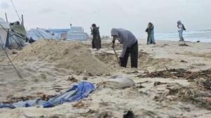 　海沿いのテント近くで、浸水対策のため砂浜を掘る人＝４日、ガザ南部ハンユニス（共同）