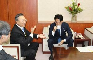 小泉進次郎農相(右)に、お湯に浸した2種類のおかきの香りを嗅いでもらい、違いを説明する岩塚製菓の槇春夫会長=東京・霞が関の農林水産省