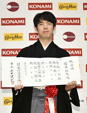 就位状を手にする藤井聡太棋王=7月2日午後、東京都内