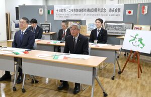 オンライン会談する関口芳史市長(左)ら。右は姉妹都市50周年を記念するロゴマーク=十日町市役所