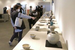 作家らと言葉を交わしながら、じっくりと作品を見て回る来場者=佐渡市中原