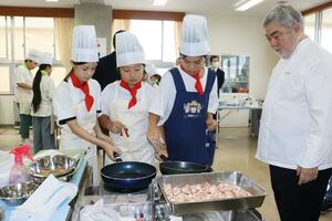 三國清三シェフ(右)が見守る中、地元食材を使ってコース料理を作る両川小の児童たち=新潟市江南区酒屋町