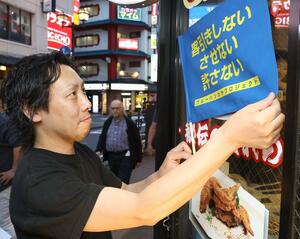 「客引きしない させない 許さない」とプリントされた旗を店舗前に掲げる飲食店の関係者=新潟市中央区弁天1