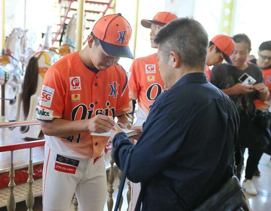 メリーゴーランドの前で、サインに応じるオイシックス新潟アルビレックスＢＣの鈴木颯人投手＝１１月４日、サントピアワールド