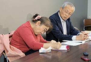 レゾナック・ホールディングスの髙橋秀仁社長に伝えたい思いなどを記す古山知恵子さん(左)=21日、県庁