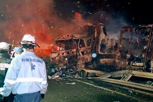 関越自動車道の事故現場で焼けた車と、活動する消防関係者ら=27日午前3時3分、群馬県みなかみ町