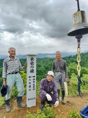 「出会の鐘」の標柱を建て替えた堀之内山の会の会員ら＝魚沼市の御嶽山（堀之内山の会提供）