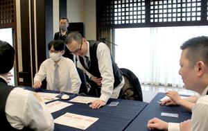 生理痛の痛みを疑似体験する男性従業員＝新発田市