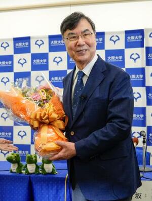 ノーベル生理学・医学賞の受賞が決まり、記者会見場で花束を手に笑顔を見せる大阪大の坂口志文特任教授=6日午後8時3分、大阪府吹田市