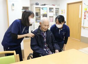 ケアセンターうしろやまで、利用者に明るい笑顔で接するモモミンアウンさん（右）＝２月、佐渡市宮川