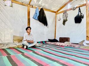 暮らしているテントの中で座るアブドラ君=10月23日、ガザ南部ハンユニス(共同)