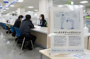 カスハラ対策の啓発ポスターが掲示された窓口で対応する市職員=新潟市中央区役所