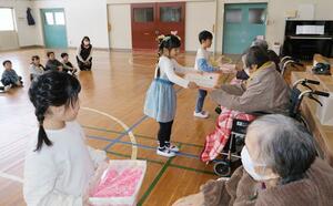 園児に手製のコサージュを贈る「加治川の里」の利用者=新発田市下小中山