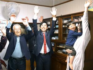 家族や親戚らと初当選を万歳で祝う本保慎吾さん=4月23日午後9時過ぎ、粟島浦村内浦