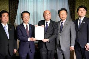 政治資金規正法の改正案を衆院事務総長(中央)に提出する国民民主と公明両党の議員=19日午後、国会