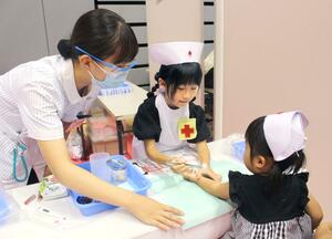 看護師の仕事体験で傷の手当てをする子ども＝長岡市大手通１