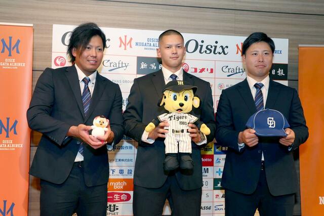 記念撮影に応じる、オイシックスの左から知念大成外野手、能登嵩都投手、牧野憲伸投手＝新潟日報メディアシップ