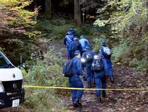 現場に向かう山道に入る警察官ら=19日午前10時45分、福岡県八女市