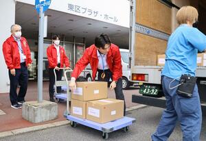 投票用紙などが入った段ボール箱を運ぶ選管職員＝３０日、新潟市東区